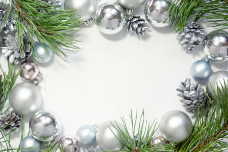 Light Christmas background with silver balls, cones and pine branches on a white background. New Year celebration.の写真素材