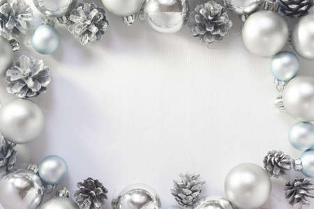 Light Christmas background with silver balls and pine cones on a white background. New Year celebration.の写真素材