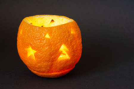 Candlestick made of orange peel on a black background. Handmade decor for New Years and Christmas celebrationsの写真素材