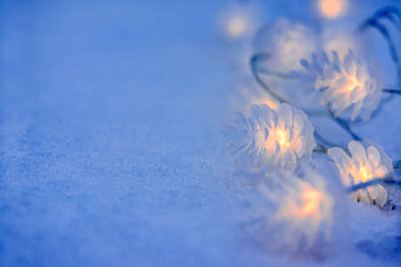 Christmas garland in the form of cones on the snow in the evening. New year festive backgroundの写真素材