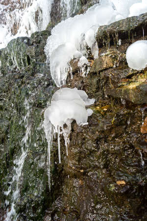 Ice frozen on the edge of the waterfall in a frosty winter. Cold day by the riverの写真素材