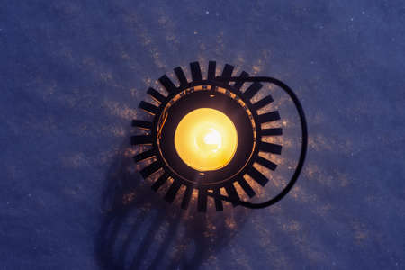 A candle in a round candlestick in the snow at night. Christmas mood of a festive eveningの写真素材