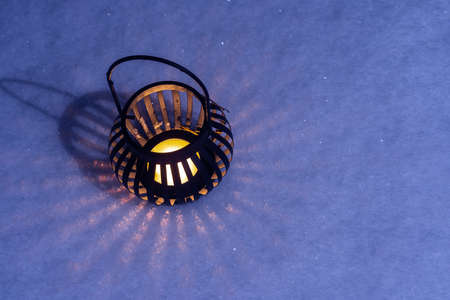 A candle in a round candlestick in the snow at night. Christmas mood of a festive eveningの写真素材
