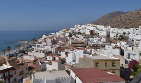 view of the houses of Castell de Ferro from above with the lighthouse over the mountain and the road in the background next to the seaのeditorial素材