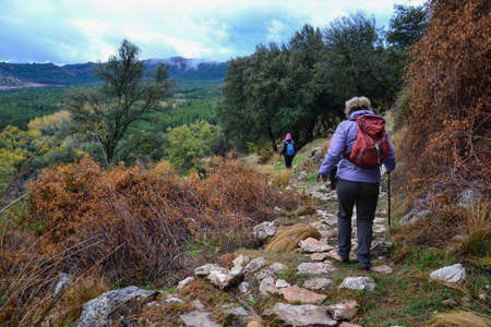 group of hikers walking along a path in the Sierra de Huetor in autumn on a cloudy day with mountains in the backgroundの写真素材