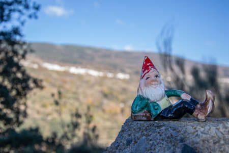 forest gnome with red cap lying posing on a stone in the fieldの写真素材