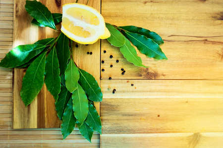  Fresh bay leaves and lemon lay on wooden cutting board.  の写真素材