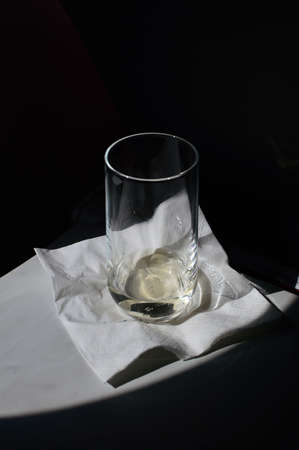a glass of champagne with a ray of sun caught from the porthole on board in an airplane on a folding tableの写真素材