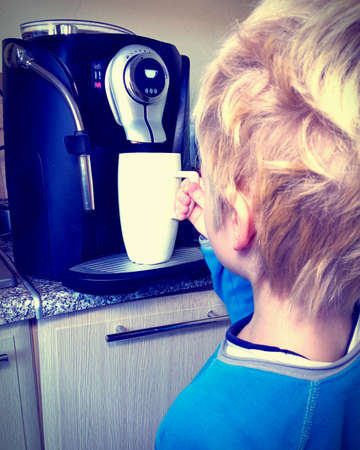 child makes coffee using a coffee machineの写真素材
