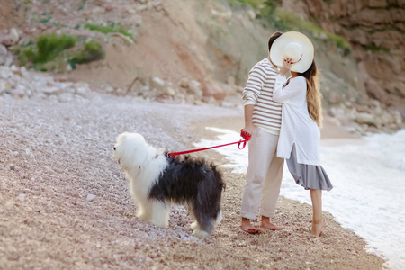 Happy young couple walking with big dog on the beach in summerの写真素材