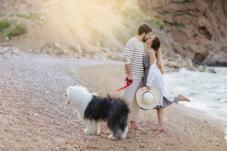 Happy young couple walking with big dog on the beach in summerの写真素材