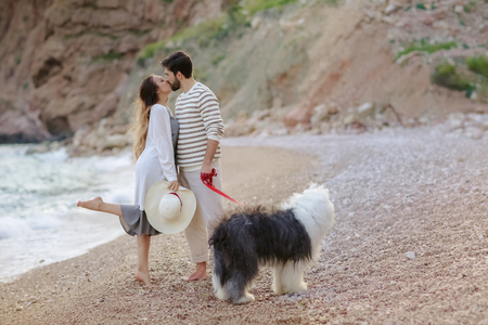 Happy young couple walking with big dog on the beach in summerの写真素材