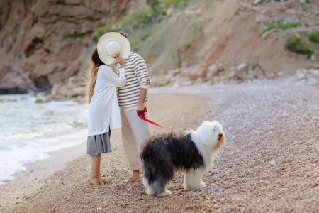 Happy young couple walking with big dog on the beach in summerの写真素材