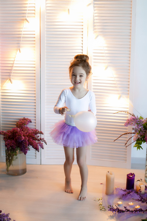 Adorable little girl dressed as a ballerina in a tutu, tying her ballet slippers.の写真素材