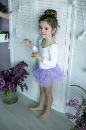 Adorable little girl dressed as a ballerina in a tutu, tying her ballet slippers.の写真素材