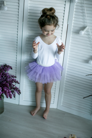 Adorable little girl dressed as a ballerina in a tutu, tying her ballet slippers.の写真素材