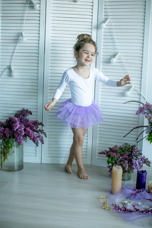 Adorable little girl dressed as a ballerina in a tutu, tying her ballet slippers.の写真素材