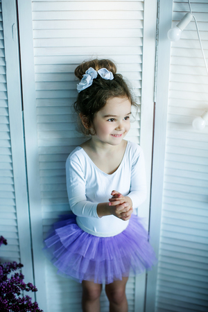 Adorable little girl dressed as a ballerina in a tutu, tying her ballet slippers.の写真素材
