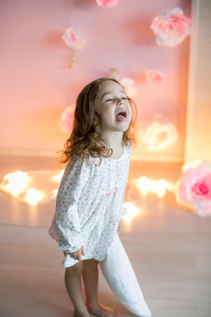 Little beautiful girl with light pillows in a cozy room.の写真素材