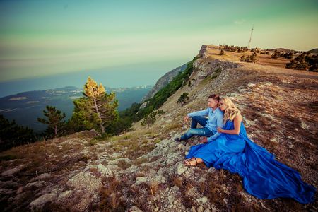 Beautiful couple of newlywed hugging at wedding day on cliff with ocean view. Stylish bride and elegant groom look at each other with love. Concept honeymoon, family, marriage, just marriedの写真素材