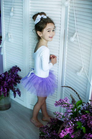 Adorable little girl dressed as a ballerina in a tutu, tying her ballet slippers.の写真素材