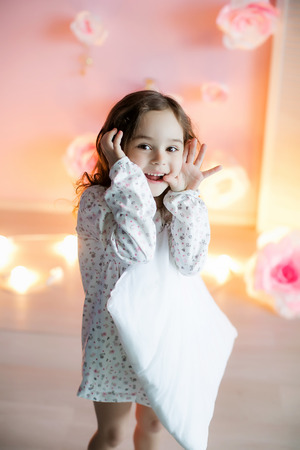 Little beautiful girl with light pillows in a cozy room.の写真素材