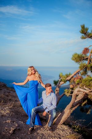 Beautiful couple of newlywed hugging at wedding day on cliff with ocean view. Stylish bride and elegant groom look at each other with love. Concept honeymoon, family, marriage, just marriedの写真素材