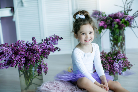 Adorable little girl dressed as a ballerina in a tutu, tying her ballet slippers.の写真素材