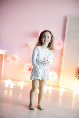 Little beautiful girl with light pillows in a cozy room.の写真素材
