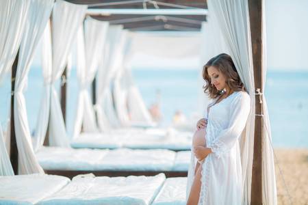 Beautiful pregnant woman on the beach in bungalowの写真素材