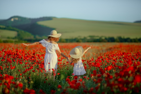 Beauty mother with teen enjoy summer days .Cute fancy dressed girl in poppy field. Field of blooming poppiesの写真素材