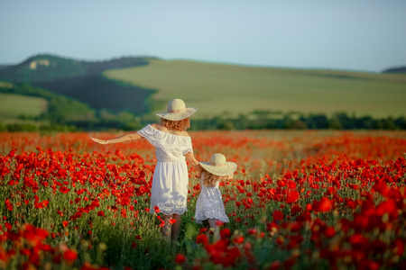 Beauty mother with teen enjoy summer days .Cute fancy dressed girl in poppy field. Field of blooming poppiesの写真素材
