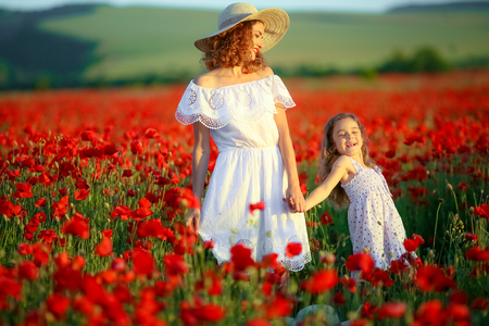 Beauty mother with teen enjoy summer days .Cute fancy dressed girl in poppy field. Field of blooming poppiesの写真素材