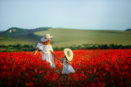 Beauty mother with teen enjoy summer days .Cute fancy dressed girl in poppy field. Field of blooming poppiesの写真素材