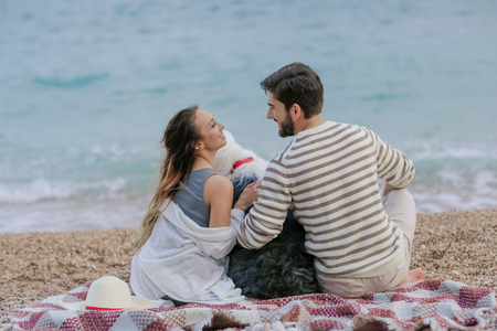 Couple of lovers on the beach. Dressed in warm spring knitted sweaters. Dinner outdoors in the open airの写真素材
