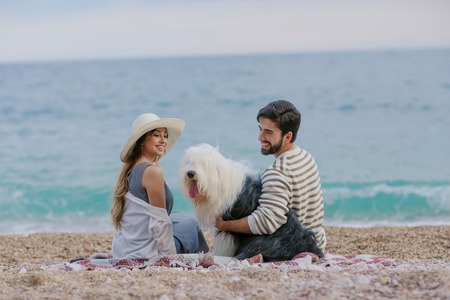 Couple of lovers on the beach. Dressed in warm spring knitted sweaters. Dinner outdoors in the open airの写真素材