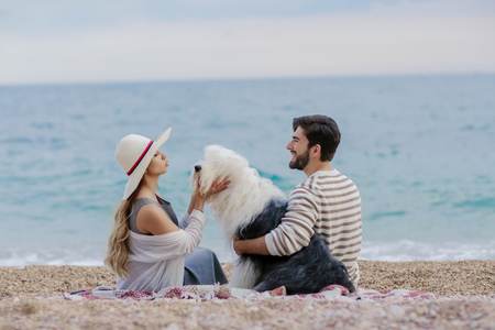 Couple of lovers on the beach. Dressed in warm spring knitted sweaters. Dinner outdoors in the open airの写真素材