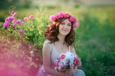 A bride in a white dress holds a bouquet of roses and callas on the background of green grassの写真素材
