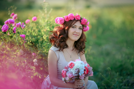 A bride in a white dress holds a bouquet of roses and callas on the background of green grassの写真素材