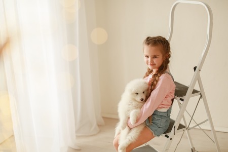 Baby Hugs the white fluffy puppy. Kids.の写真素材