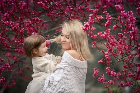 young mother with adorable daughter in park with blossom tree. Happy mother and childの写真素材