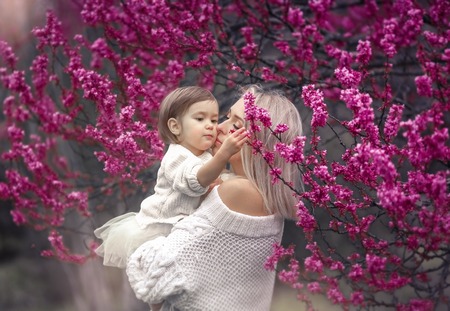 young mother with adorable daughter in park with blossom tree. Happy mother and childの写真素材