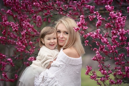 young mother with adorable daughter in park with blossom tree. Happy mother and childの写真素材