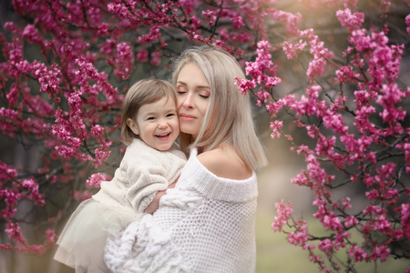 young mother with adorable daughter in park with blossom tree. Happy mother and childの写真素材