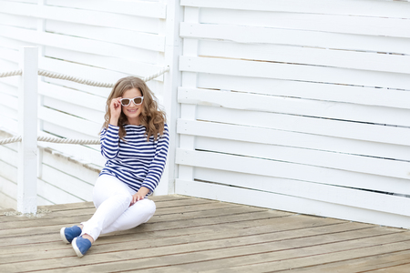 curly woman take a photo at wooden background in a stylish white jeansの写真素材