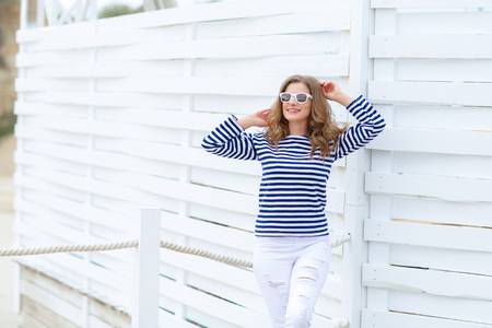 curly woman take a photo at wooden background in a stylish white jeansの写真素材