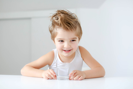 Cute smiling boy with glass of water isolated on a white background.の写真素材