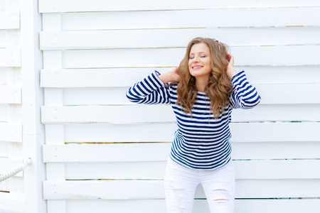 curly woman take a photo at wooden background in a stylish white jeansの写真素材