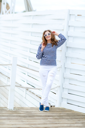 curly woman take a photo at wooden background in a stylish white jeansの写真素材