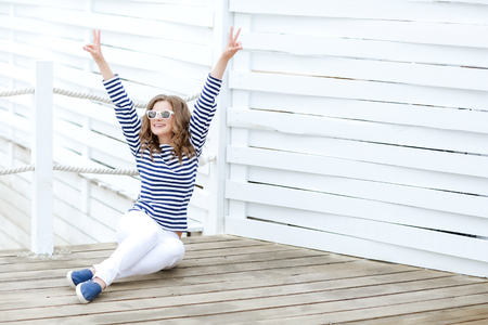 curly woman take a photo at wooden background in a stylish white jeansの写真素材